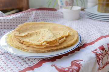 traditional french homemade pancakes in a plate served on a table with red and white tablecloth