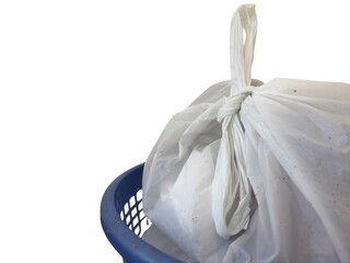 A close-up view of a blue plastic laundry basket, containing a white, securely tied-off plastic...