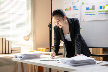 A woman is sitting at a desk with a whiteboard behind her