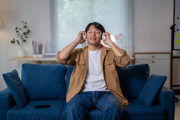 A man is sitting on a blue couch listening to music