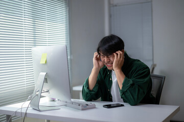 A man is sitting at a desk with a computer monitor in front of him