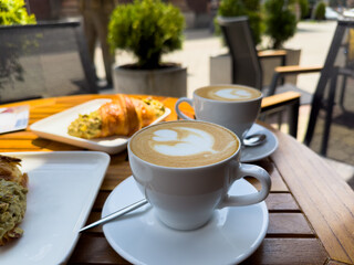 A white coffee cup of cappuccino on a wooden table with a plate of croissants. breakfast in cafe, Paris morning, Europe morning. High quality photo