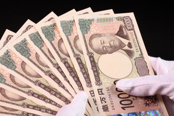 白手袋で1万円札を持つ