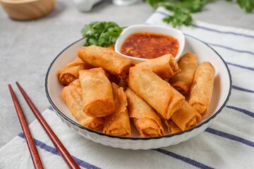 Deep fried vegetable spring rolls or egg rolls and sauce , Thai called popia in white  plate on grey background	