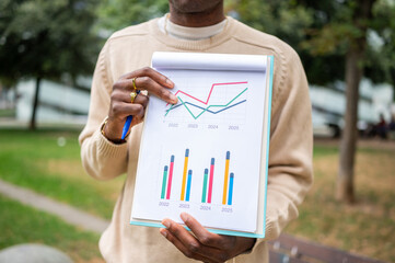 Businessman examining financial charts in a park setting