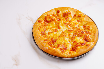 Cheese pizza on a black plate placed on a white marble surface