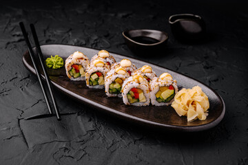 Fresh sushi rolls served on a black plate with wasabi and ginger