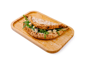 Freshly made flatbread filled with greens and cheese served on a wooden tray