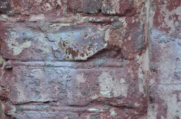 Aged brick wall with peeling paint and weathered texture, rustic rough surface, old urban decay, red and grey cracked facade close-up, historic masonry texture background