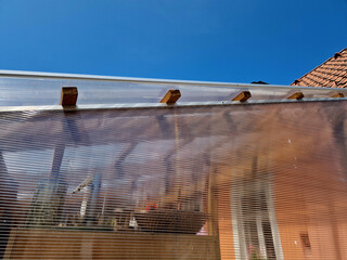 terrace with wooden pergola and plexiglass roof. vines are straining, crawling under the beams....