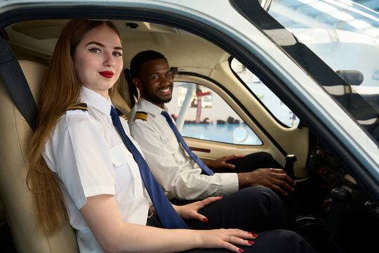 Smiling student pilots sitting in cockpit of small airplane