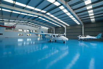Modern aircraft hangar with training airplanes parked on blue floor