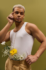 Young man flaunts trendy style with flowers in a stylish studio setting