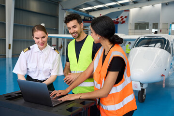 Aviation students and pilot using laptop in aircraft hangar