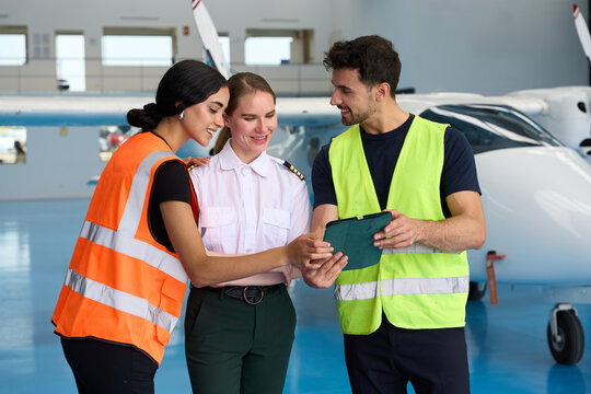 Aviation students and pilot using tablet in hangar