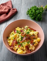 Potato sald with fresh herbs , scrambled eggs and bacon in a pale pink ceramic bowl on gray wooden table. Generated image