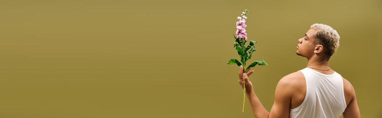 Young man with dyed hair and flowers showcases modern style in studio setting