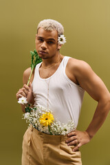 Young man in trendy tank top holds flowers with style in a vibrant studio setting