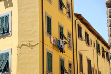View of clotheslines outside the windows with clothes airing out to dry on residential building in Italy.