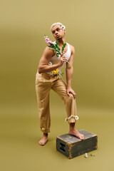 Young man flaunts trendy style with flowers in vibrant studio setting
