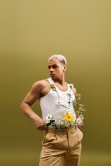 Young stylish man with dyed hair showcases trendy flower-inspired fashion in studio