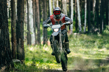 Enduro rider on bike rear wheel speeding through muddy forest trail