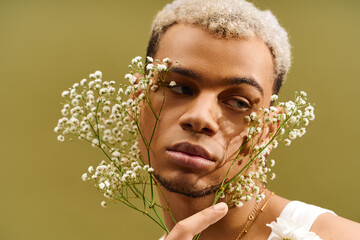 Young man showcasing trendy style with flowers in a vibrant studio setting