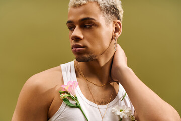 Young man radiates style in trendy tank top with flowers in studio setting