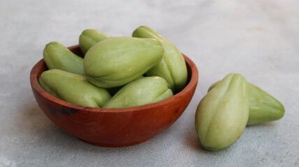 Baby chayote (labu siam) on wooden bowl with grey background