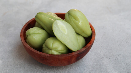 Baby chayote (labu siam) on wooden bowl with greybackground