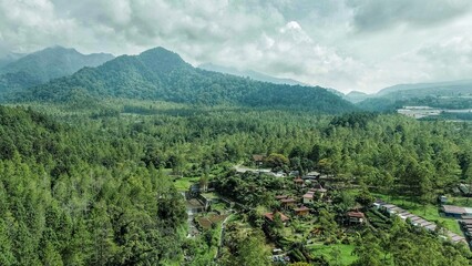 Beautiful aerial of landscape village in the middle of green nature in foot of mountain with blue sky background
