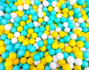 A full-frame, top-down view of a colorful ball pit filled with a bright mixture of yellow, light blue (cyan), and white plastic balls.