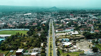 Beautiful aerial view of the highway between buildings and houses with mountains and blue sky background