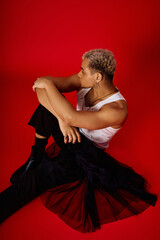 Trendy young man showcasing unique fashion in vibrant red studio setting