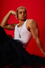 Young African American man showcases bold style in trendy red studio setting