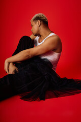 Trendy young man with dyed hair poses stylishly in red studio setting