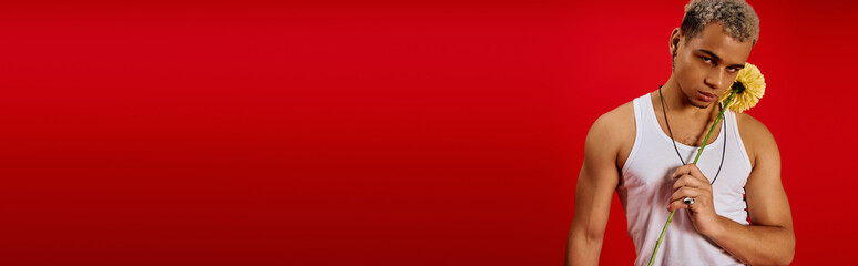 Trendy young man with dyed hair showcases style in a vibrant red studio setting