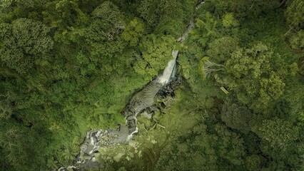 Beautiful view of aerial Fresh Flow of waterfall from natural spring in the middle of the green lush nature forest