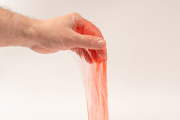 Red slime toy in man hand isolated on white.