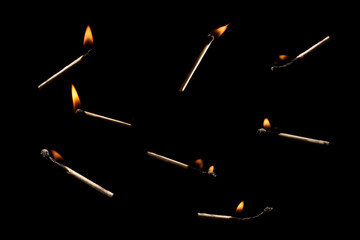 Lit falling match on a black background.