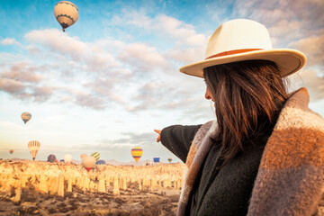 Caucasian woman on viewpoint over love valley watch hot air balloon flight show point finger on...
