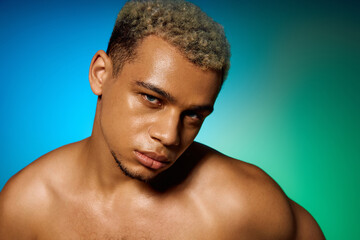 Muscular young man with dyed hair poses confidently in a vibrant studio setting