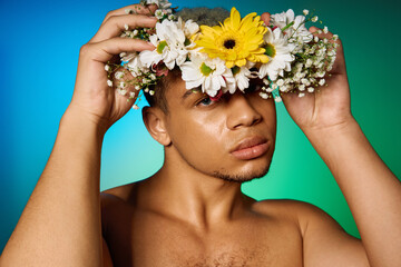 Young man with dyed hair poses elegantly in studio adorned with floral crown