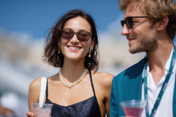 Elegant couple smiling and enjoying drinks at outdoor event