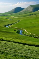 A winding river flows through expansive green fields beneath gently rolling hills under a blue sky with scattered clouds.
