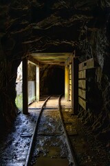 Fototapeta premium A view of the historic Karangahake gold mine tunnel in New Zealand. The tunnel was built to extract gold ore, and the tracks remain as a reminder of the mining history.