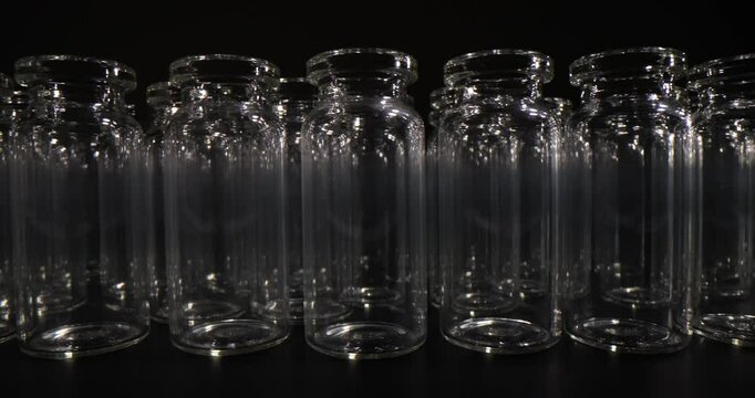 Small empty glass vials collection on black background. Sterile flasks prepared for medical products package in pharmaceutical facility