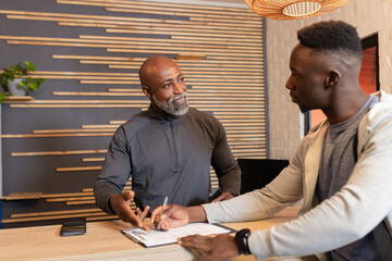 African American trainer and client filling health forms at reception desk using clipboard and pen