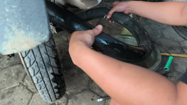 a motorcycle workshop technician is inspecting a leak in the motorcycle tire