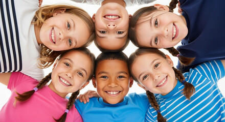 A diverse group of six smiling children form a circle with their heads together, looking up